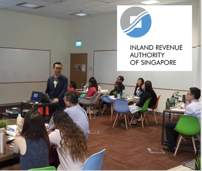 Wei Kian presenting to participants seated around tables during a workshop at IRAS
